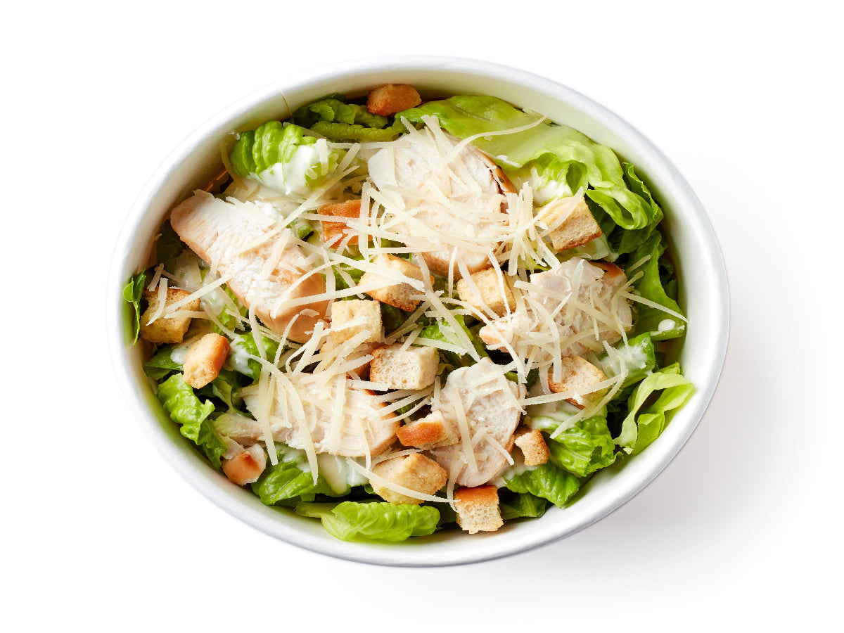 A bowl of salad mixed with chicken cubes, iceberg lettuce, onions, cucumbers, tomatoes, making a delicious offering.