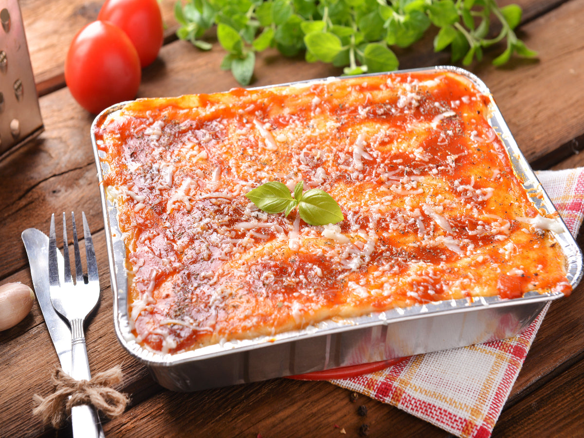Cheese lasagna packed in an aluminum foil packaging on a table