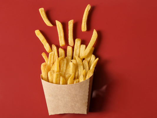 Golden crispy French fries served on a red table